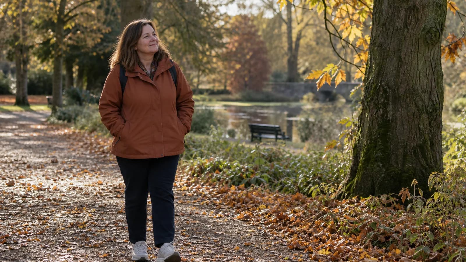 A midlife woman enjoying an unhurried walk on an autumn park path